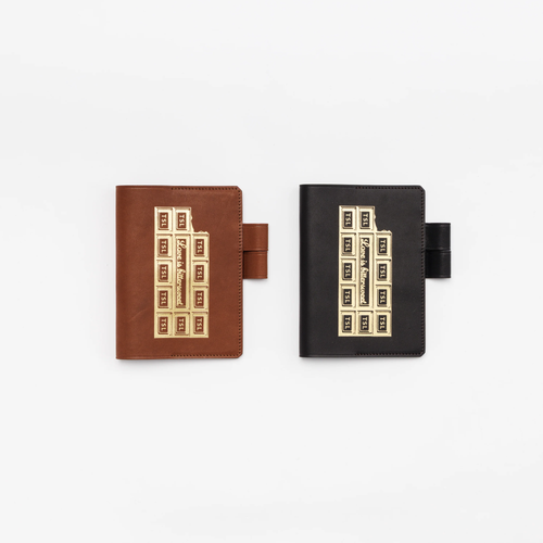 THE SUPERIOR LABOR A6 Note Keeper - Chocolate. A handcrafted leather notebook cover designed to look like a chocolate bar with a foil wrapper. Protège-carnet A6 Chocolat par THE SUPERIOR LABOR. Une couverture de carnet en cuir artisanal ressemblant à une tablette de chocolat avec emballage.