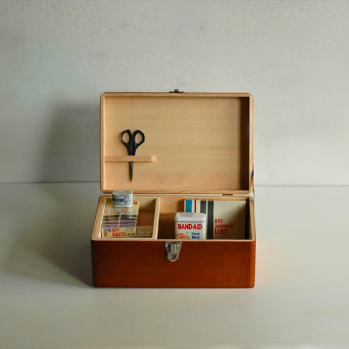 Classiky small Toga wood first aid box with a vintage design, metal latch, and folding top handle. Open view shows a removable sliding tray and a metal clip inside the lid. / Petite boîte à pharmacie Classiky en bois de Toga au design vintage, avec loquet métallique et poignée rabattable. La vue ouverte montre un plateau coulissant amovible et un clip en métal à l'intérieur du couvercle.