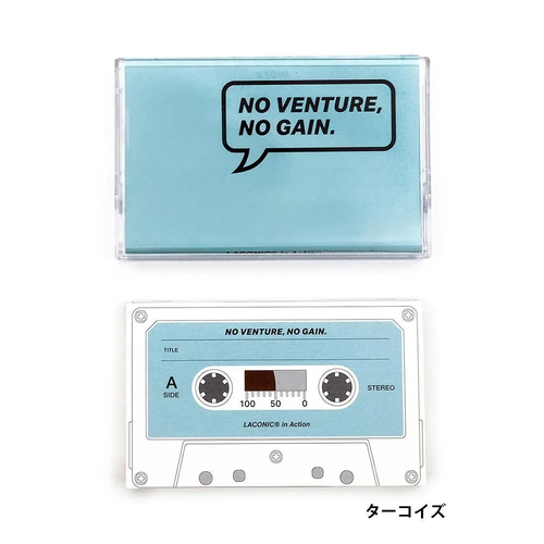 LACONIC in Action Turquoise cassette tape-shaped notebook shown inside its clear plastic case alongside its retro index sheet. / Carnet LACONIC in Action Turquoise en forme de cassette audio présenté dans son boîtier en plastique transparent avec sa fiche d'index rétro.