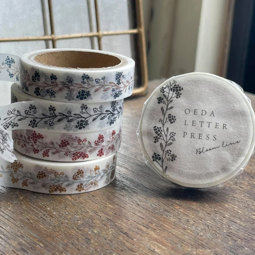OEDA LETTERPRESS Bloom Line 10mm Japanese washi masking tape featuring a delicate continuous floral path illustration. / Ruban masquage washi japonais OEDA LETTERPRESS Bloom Line 10mm présentant une illustration délicate de chemin fleuri continu.