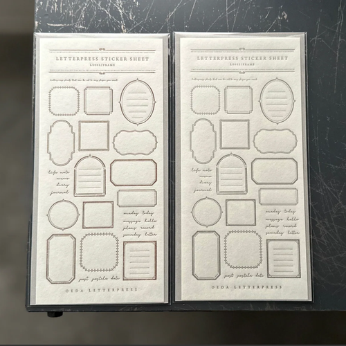 OEDA LETTERPRESS Sticker Sheet Frame in Bronze and Greige displaying various press-printed vintage frame shapes on heavy adhesive paper. / Feuille d'autocollants OEDA LETTERPRESS Frame en Bronze et Grège présentant diverses formes de cadres vintage imprimées sur papier adhésif épais.