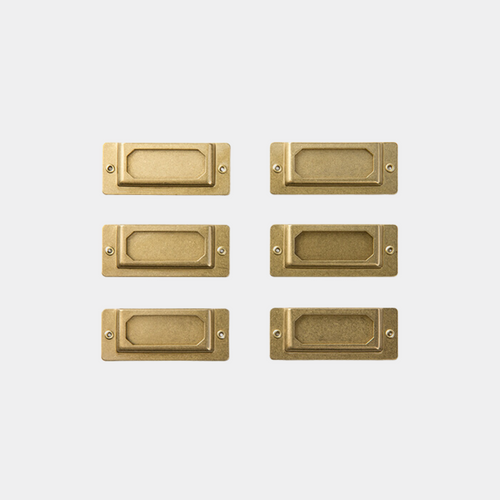 TRAVELER'S COMPANY BRASS Label Plates. A set of six vintage-style solid brass plates for indexing notebooks and boxes. Plaques d'étiquettes en laiton TRAVELER'S COMPANY. Un ensemble de six plaques en laiton massif au style vintage pour indexer carnets et boîtes.