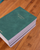 Faded Chronicle 2027 Chronicle Planner B6 Compact edition showing a collection of its 10 unique cover options with an open view of its lay-flat ink-friendly pages. Agenda Faded Chronicle 2027 Chronicle Planner Édition B6 Compact, présentant ses 10 options de couverture uniques et ses pages intérieures plates adaptées aux stylos plume.
