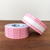 A roll of Stamp Marche adhesive label stickers in a soft pink gingham check pattern. The stickers are rectangular with rounded corners, designed for planners and sealing. Un rouleau d'autocollants adhésifs Stamp Marche au motif à carreaux vichy rose clair. Les étiquettes sont rectangulaires avec des coins arrondis, parfaites pour les agendas et le scellement d'enveloppes.