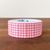 A roll of Stamp Marche adhesive label stickers in a soft pink gingham check pattern. The stickers are rectangular with rounded corners, designed for planners and sealing. Un rouleau d'autocollants adhésifs Stamp Marche au motif à carreaux vichy rose clair. Les étiquettes sont rectangulaires avec des coins arrondis, parfaites pour les agendas et le scellement d'enveloppes.