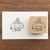 A square Japanese rubber stamp (a-089) featuring the character Marl-chan sitting and using a small rubber stamp on a piece of paper, celebrating the joy of stamping and crafting. Un tampon en caoutchouc japonais carré (a-089) illustrant le personnage Marl-chan assise en train d'utiliser un petit tampon sur une feuille de papier, célébrant la joie de l'estampage et de l'artisanat.