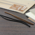 TRAVELER'S Notebook 021 Connecting Bands for Regular Size notebook inserts shown in classic black and brown rubber. / Bandes de connexion TRAVELER'S Notebook 021 pour recharges taille Régulière présentées en caoutchouc noir et marron classique.
