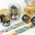 HIGHTIDE x Moomin PET Tape (Moomin Valley Friends), a transparent masking tape roll featuring colorful Moomin character illustrations. Ruban adhésif transparent (PET) HIGHTIDE x Moomin (Les amis de la Vallée), présentant des illustrations colorées des personnages Moomin.