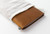 TRAVELER'S Notebook Starter Kit Regular Size in Camel. A warm tan leather cover with a blank refill, green spare elastic, and a cotton bag. Kit de démarrage TRAVELER'S Notebook Taille Régulière en Camel. Une couverture en cuir havane avec une recharge vierge et un élastique de rechange vert.