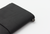 TRAVELER'S Notebook Starter Kit Regular Size in Black. A sleek black leather cover with a blank white refill, red spare elastic, and a cotton bag. Kit de démarrage TRAVELER'S Notebook Taille Régulière en Noir. Une couverture en cuir noir élégante avec une recharge vierge, un élastique rouge et un sac en coton.