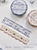 Pion Washi Deco Tape Cherry. A 1.5cm wide washi tape with shaped edges featuring a continuous pattern of illustrated red cherries. Ruban adhésif Washi déco Pion Cherry (櫻桃). Un ruban de 1,5 cm aux bords découpés illustrant un motif continu de cerises rouges.
