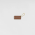 THE SUPERIOR LABOR Leather Tag - Chocolate. A handcrafted leather charm designed to look like a chocolate bar in a silver foil wrapper. Étiquette en cuir THE SUPERIOR LABOR - Chocolat. Un charm artisanal en cuir conçu pour ressembler à une tablette de chocolat dans son emballage argenté.