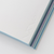 TAKEO PAPER SIKI Notebook M in Tsuyu Rainy Blue showcasing its unique sloped side profile featuring 51 different blue and cool-toned textured paper sheets. / Carnet TAKEO PAPER SIKI Taille M thème Tsuyu Pluie Bleue montrant son profil en biseau unique composé de 51 feuilles de papiers bleus aux textures différentes.