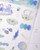 dodolulu Matte Sticker Sheet Waves of Blue featuring soothing ocean tides and blue-themed illustrations. / Planche d'autocollants mats dodolulu Waves of Blue présentant des marées apaisantes et des illustrations dans les tons bleus.