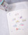 dodolulu Label Sticker Roll Reverie made of textured washi paper with shimmering foil stamping featuring 8 repeating designs. / Rouleau d'étiquettes autocollantes dodolulu Reverie en papier washi texturé avec dorure étincelante présentant 8 motifs répétés.