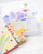 dodolulu 2027 Monthly Calendar Stickers set featuring 12 die-cut calendar cards and 15 decorative stickers with a subtle sand glitter finish in a keepsake box. / Ensemble d'autocollants calendrier mensuel 2027 dodolulu comprenant 12 cartes de calendrier découpées et 15 autocollants décoratifs avec une finition pailletée sablée dans une boîte souvenir.
