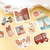 BGM Piece of The Journey Sticker Set To The World. A foil-stamped flake pack of 45 world-travel stickers (15 designs × 3) in a 90 × 100 mm sleeve. Set d’autocollants BGM Piece of The Journey To The World. 45 stickers voyage dans le monde dorés (15 motifs × 3), pochette 90 × 100 mm.