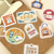 BGM Retro Stroll Sticker Set Stationery Store. A foil-stamped flake pack of 45 stationery-shop stickers (15 designs × 3) in a 90 × 100 mm sleeve. Set d’autocollants BGM Retro Stroll Stationery Store. 45 stickers papeterie dorés (15 motifs × 3), pochette 90 × 100 mm.