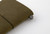 TRAVELER'S Notebook Starter Kit Passport Size in Olive. A forest-green leather cover with a blank refill, blue-gray spare elastic, and a cotton bag. Kit de démarrage TRAVELER'S Notebook Taille Passeport en Olive. Une couverture en cuir vert forêt avec une recharge vierge et un élastique de rechange bleu-gris.
