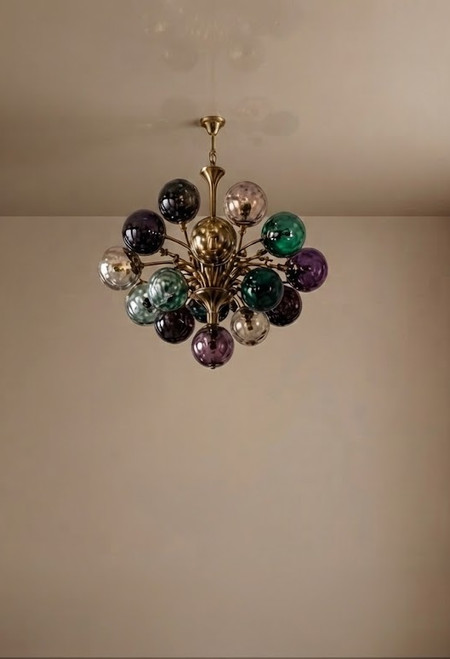 Fiella chandelier, multi-colored glass chandelier, art deco lighting, luxury brass chandelier, designer ceiling light, bespoke lighting fixture, high-end interior design, hand-blown glass spheres, jewel-tone lighting, brushed brass armature, modern Italian design, residential lighting, boutique hospitality lighting, custom chandelier design, luxury living room lighting, architectural lighting fixture, statement ceiling pendant, designer light fixture, interior design specification, emerald green glass, deep purple glass, smoked amber glass, textured glass spheres, contemporary lighting art, upscale home decor, luxury dining room lighting, moody library decor, bespoke brass fixture