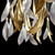 Zoom in and behold the mesmerizing beauty of a close-up view of a luxury white and gold glass feather chandelier. Each delicately crafted glass feather showcases an exquisite fusion of white and gold, capturing the essence of opulence. The feathers, meticulously shaped and adorned with intricate gold accents, radiate a luminous glow that emanates from within. The play of light and shadow creates a captivating dance, accentuating the intricate details and adding depth to the feathers' ethereal presence. The lustrous gold embellishments delicately trace the contours of each feather, shimmering with an enchanting allure. This close-up view unveils the craftsmanship and artistry that goes into creating such a masterpiece, revealing the intricate textures and impeccable precision. It is a symphony of elegance and sophistication, inviting you to appreciate the meticulous craftsmanship and immerse yourself in the captivating allure of this extraordinary white and gold glass feather chandelier.