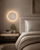 Solara natural travertine wall light used as a luxury bedside wall sconce in a neutral Wabi Sabi bedroom with warm ambient LED lighting