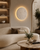 Solara Wabi Sabi natural stone wall light in a luxury living room with curved furniture, travertine details and warm contemporary interior lighting