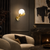 Liora Surrealist Gold Hand Wall Light in Luxury Living Room
The Liora sculptural gold hand wall light displayed against deep charcoal panelling in an elegant contemporary living room, where its illuminated opal globe, polished gold finish and Surrealist form complement marble, bouclé seating and sophisticated dark-toned décor.