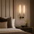 America Brass & Glass Wall Sconce – Luxury Bedroom Interior
America brass and glass double wall sconce installed beside a luxury upholstered bed in an elegant boutique hotel-style bedroom. Featuring tall fluted glass shades, warm brass detailing and black accents, this decorative wall light is ideal for luxury bedrooms, hotel suites and refined bedside lighting schemes.