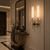 America Art Deco Wall Light – Luxury Hallway & Entrance Interior
America Art Deco double wall light displayed in a sophisticated luxury entrance hall with decorative wall moulding, marble flooring, a sculptural console table and statement mirror. The brass and black wall sconce with tall fluted glass shades is ideal for hallways, entrance halls, boutique hotels and high-end hospitality interiors.