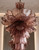 luxury interior design lighting, grand foyer chandelier, dining room statement lighting, bespoke glass pendant, hand-crafted Italian chandelier, red glass chandelier, dark pink glass chandelier, purple-red ceiling light, dramatic statement chandelier, multi-tiered glass fixture, cascading Venetian light, luxury home accent, modern baroque lighting, traditional Murano lighting, artisan handblown decor, high-end interior lighting, elegant ceiling fixture, designer art glass light, exclusive Venetian design