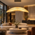 The Nami pendant light featured within a sophisticated boutique hotel-style lounge interior, suspended above a seating area with warm neutral finishes and elegant contemporary furnishings. This image highlights the pendant as a statement lighting feature for hotel lobbies, hospitality lounges and design-led commercial interiors.