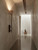 entry wall light, entryway ambient sconce, hallway torch lamp, travertine home decor, wabi sabi living room sconce, Japandi master bedroom light, stone sconce online, buy travertine wall lamp, 71cm tall light fixture, 12cm width sconce, slim profile wall light, space saving bedside light, flush backplate sconce, dark walnut sconce, matte black fixture rod, natural stone cup shade, hand finished stone light, luxury indoor sconces, soft glow wall lamp, architectural uplight fixture, organic texture sconce