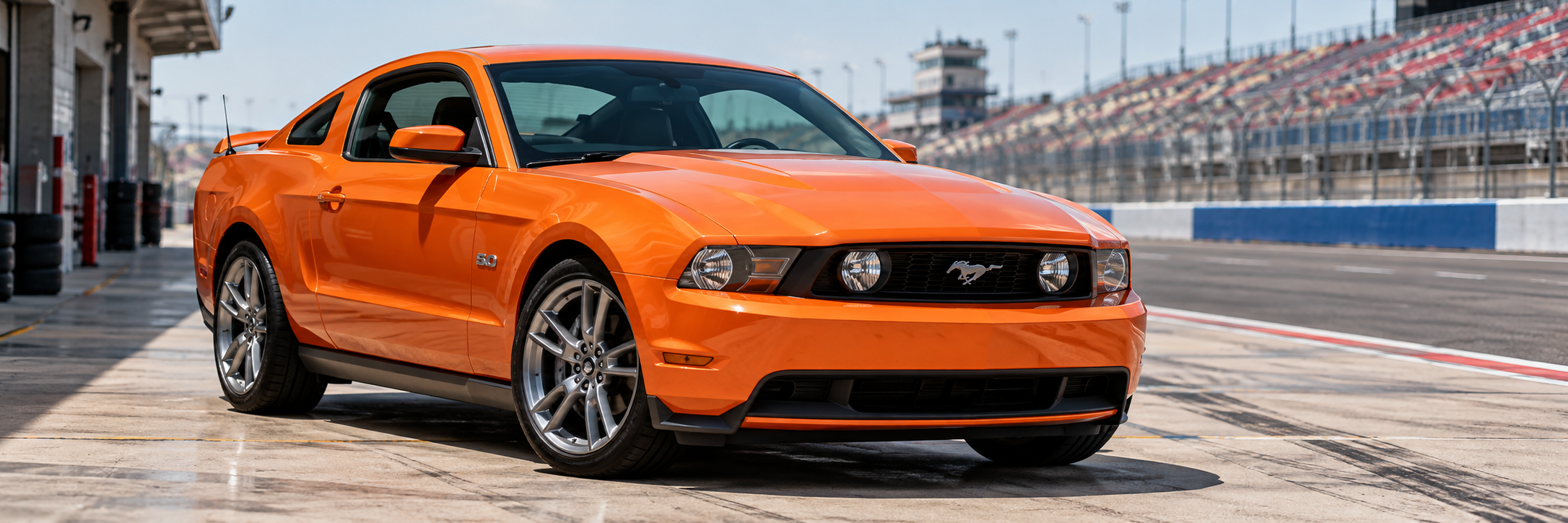 Orange S197 Mustang GT in a race circuit pit lane