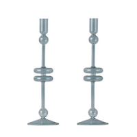 Pair of medium denim blue glass candlesticks with elegant, modern design and spherical accents.