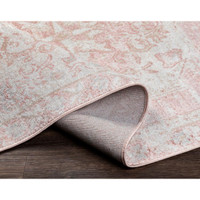 St Tropez pale pink and beige polypropylene rug with traditional design, partially rolled on a wood floor.