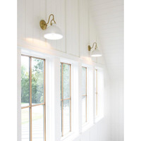 Two white ceramic Eloise sconces with natural brass accents illuminate a white paneled wall above windows.