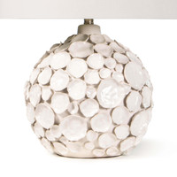 White ceramic table lamp with a round base covered in pinched disks and a linen shade.