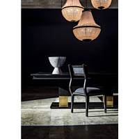 Ravenko black mahogany dining table with brass leg bands, a gray chair, and a decorative bowl under chandeliers.
