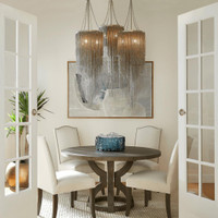 Blue cast glass decorative bowl centerpiece on a round dark wood dining table with four cream chairs.
