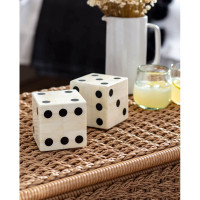 Pair of oversized bone dice with inlaid black dots on a woven surface.