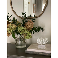 Matte white succulent resin sculpture on a clear acrylic base, next to flowers and books.