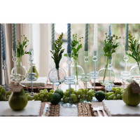 Large denim blue glass candlesticks with taper candles and floral accents on a dining table with fruit.