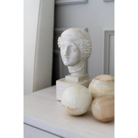 Polished natural jade spheres in varying cream and beige tones next to a white classical bust.