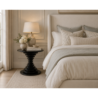 Schilling round side table with hand-rubbed black finish and concentric ring design in a bedroom.