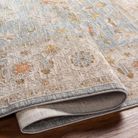 Machine-woven Avant Garde rug in pale blue and light beige with traditional floral designs, rolled at one end.