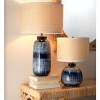 Indigo blue and white batik table lamps with textured beige shades on a rattan console.