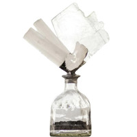 Clear glass bottle with a selenite geode, slabs, and sticks, creating a unique, organic decorative piece.