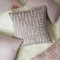 Brix Bella Blush 24x24 throw pillow with a geometric pink and brown pattern on a white shag rug.