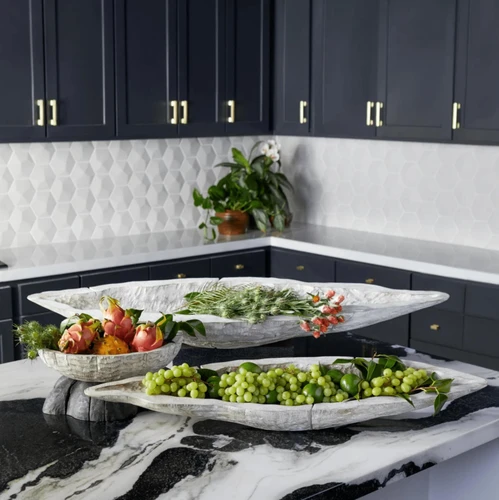 Three whitewashed Ardu wood decorative bowls on a marble counter, filled with fruit and greenery.